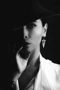 Portrait of young woman against black background