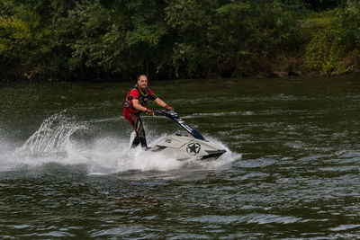 Man surfing in river against trees