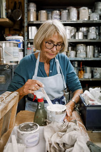 Confident senior female owner with glue working at workshop