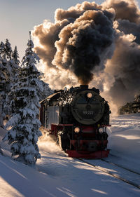 Train on snow covered railroad track against sky