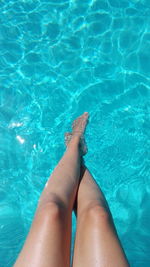 Low section of woman standing on swimming pool