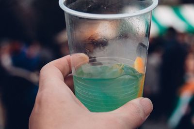 Cropped image of person holding drink in disposable glass