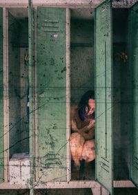 Naked woman crouching in locker