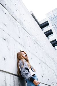 Portrait of young woman standing against wall