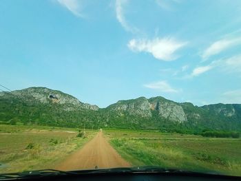 Road amidst mountains seen through car windshield