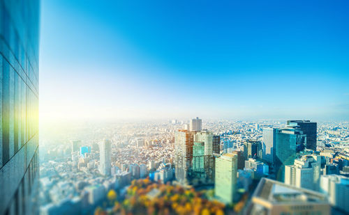 Aerial view of buildings in city against blue sky