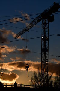 Low angle view of silhouette electricity pylon against sky during sunset