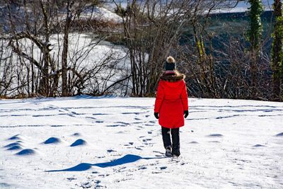 Rear view of woman walking on snow covered land