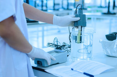 Midsection of scientist examining chemical in laboratory