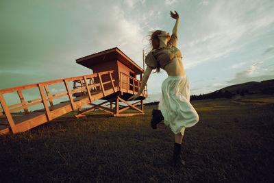 Full length of woman dancing on field against sky