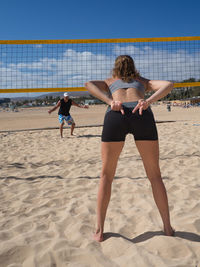 Rear view of woman with umbrella on beach against sky