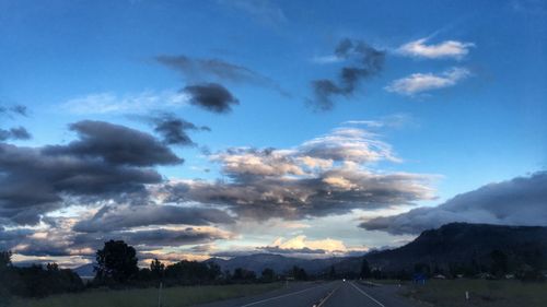 Road by trees against blue sky