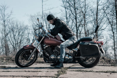 Mid adult man sitting on motorcycle in forest