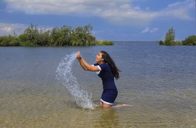 Full length of young woman in sea against sky