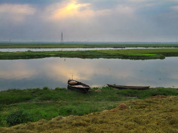 Boat moored on shore by lake against sky