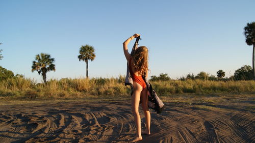 Rear view of young woman standing against clear sky