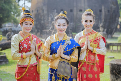 Smiling females in traditional clothing standing with hands clasped