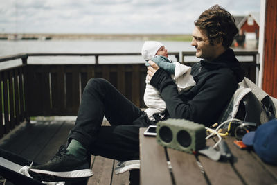 Smiling father looking at newborn baby while sitting outdoors