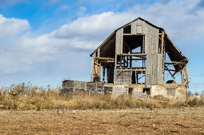 Low angle view of abandoned built structure on field against sky