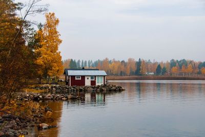 House by lake against sky during autumn