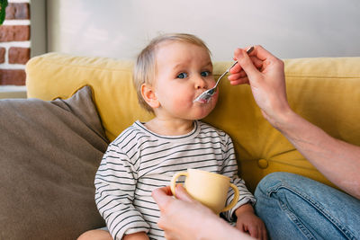 Mom feeds a small child at home with yogurt from a spoon. family concept