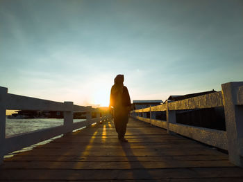 Rear view of man standing on footpath against sky