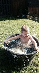 High angle view of toddler splashing water while bathing in tub at yard