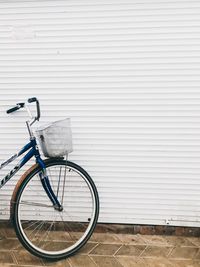 Bicycle parked against white wall