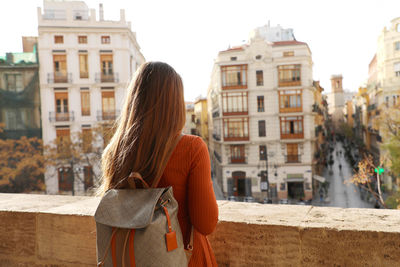 Rear view of woman standing against buildings in city