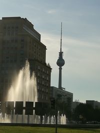 Communications tower in city against sky