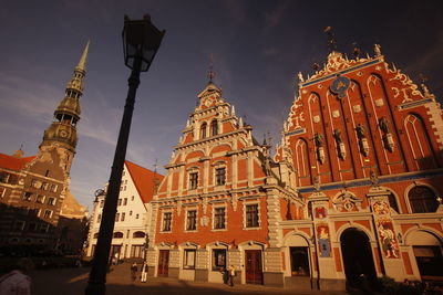 Low angle view of church by walkway against blue sky during sunny day