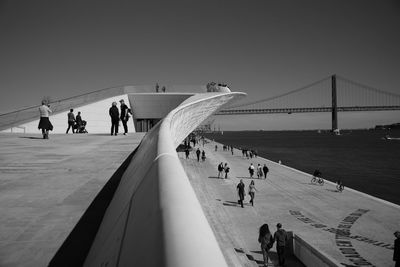 People on suspension bridge against sky