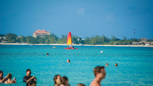 People swimming in sea against clear blue sky