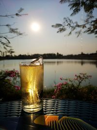 Close-up of beer glass on table against sky during sunset