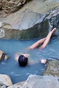 Full length of young woman relaxing in hot spring
