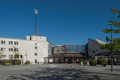 Street amidst buildings against clear blue sky