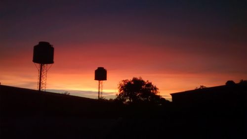 Silhouette of water tower against sky during sunset