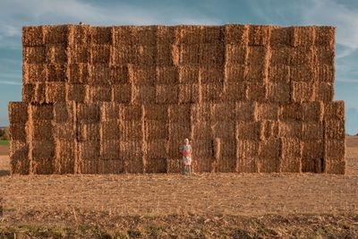 Mid adult woman standing against hay bales