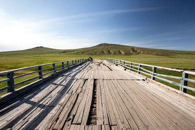 Boardwalk leading towards mountain against blue sky