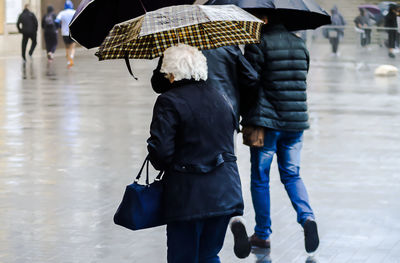 Rear view of people walking on street in rain