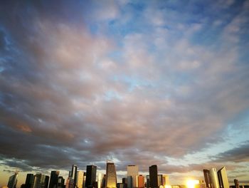 Low angle view of skyscrapers against cloudy sky