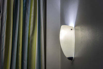 Close-up of illuminated electric lamp against wall