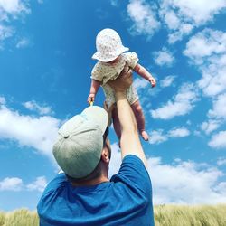 Low angle view of father and son playing on field against sky