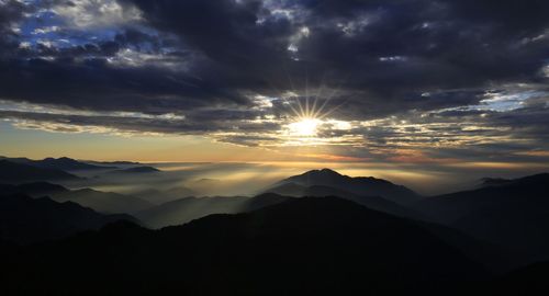 Scenic view of silhouette mountains against dramatic sky