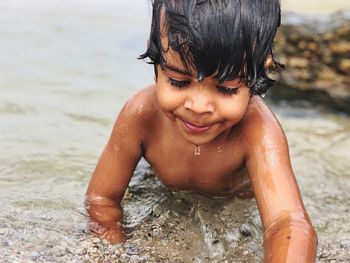 Cute shirtless boy swimming in sea