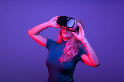 Portrait of young woman photographing against blue background