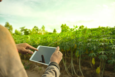 Midsection of man using mobile phone on field