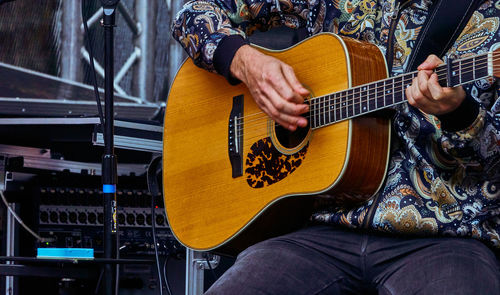 Midsection of man playing guitar