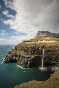 Scenic view of sea by cliff against sky