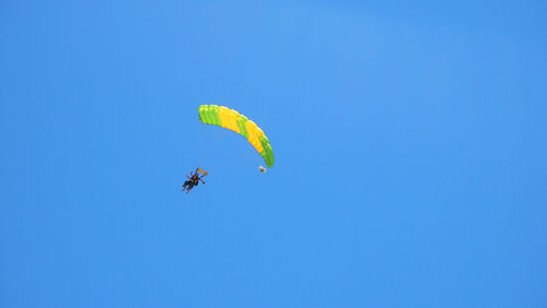 Low angle view of person paragliding against clear blue sky